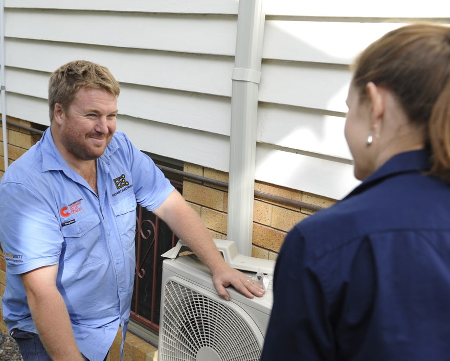 Expert electrical employee advising residential client on air conditioners