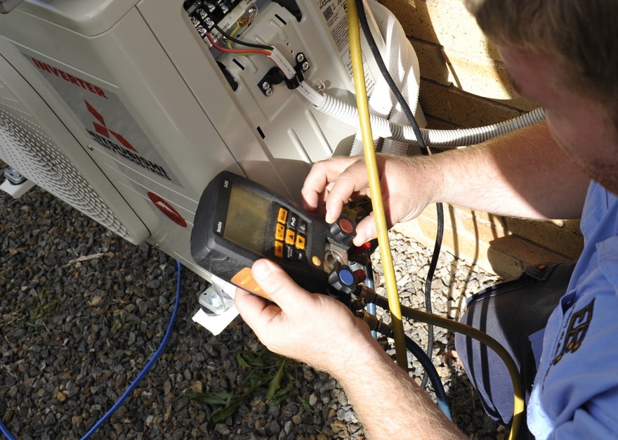 expert electrical employee testing the working status of an air conditioning unit